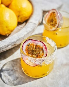 two glasses filled with orange juice next to some lemons