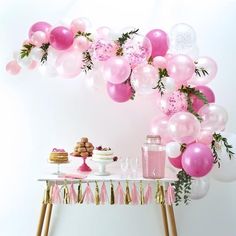 a table topped with pink and white balloons