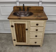 a sink made out of wood with drawers and knobs on the front, sitting next to a garage door