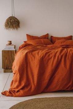 an orange comforter on a bed in a room with white walls and flooring