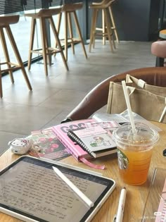 a wooden table topped with a tablet computer next to a cup of tea and a drink