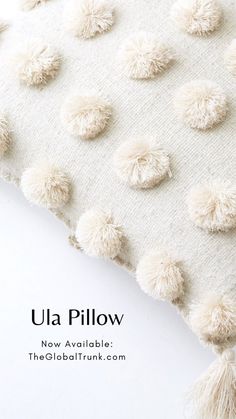 a white pillow with pom - poms on it