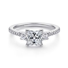 a princess cut diamond engagement ring with three stones on the band and shoulders, set in white gold