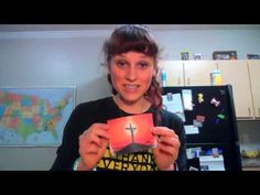 a woman holding up a small card with a cross on it