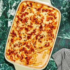 a casserole dish is shown on a green marble counter top with a striped napkin