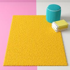 a yellow rug next to a blue cup on top of a pink and white floor