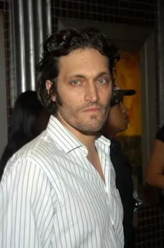 a man with curly hair and blue eyes wearing a white shirt