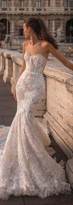 a woman in a wedding dress leaning against a wall with her hand on her hip