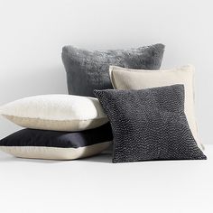 four pillows stacked on top of each other in front of a white wall and floor