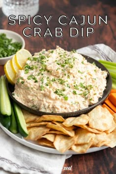 a plate with crackers, celery, and chips on it that says spicy cajun crab dip