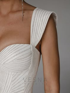 the back of a woman's white dress with silver beads on her neck and shoulder