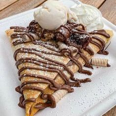 a white plate topped with chocolate covered crepes and ice cream on top of it