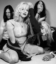 four women sitting on the floor posing for a black and white photo with one woman holding her head