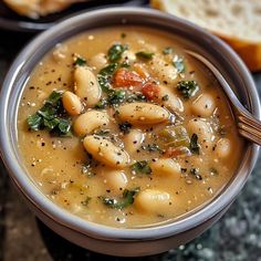 a close up of a bowl of soup with bread in the background