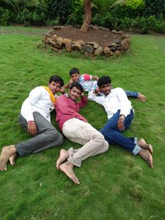 four men are laying on the grass together