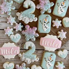 decorated cookies with numbers and snowmen are on a wooden table next to other decorations