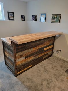 a wooden counter sitting in the middle of a room with pictures on the wall behind it