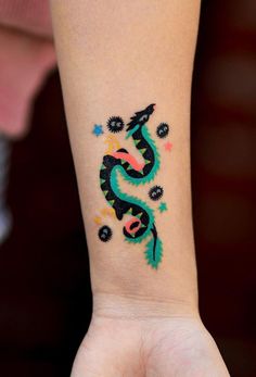 a woman's arm with a dragon tattoo on the left side of her wrist