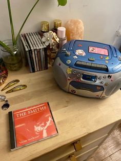 a cd player sitting on top of a wooden table next to a book and other items