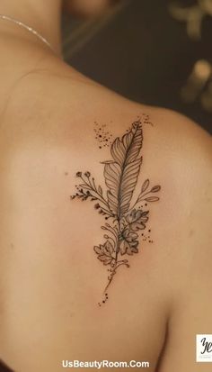 the back of a woman's shoulder with a feather and flowers tattoo on it