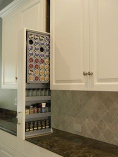 an open cabinet in the middle of a kitchen countertop with spices and condiments