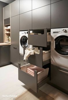 a washer and dryer in a small room with grey cabinets, white tile flooring