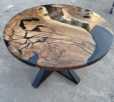 a wooden table with black metal legs and a reflection of trees in the glass top