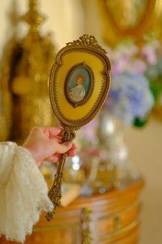 a person holding a mirror with a woman's face on it in front of a table