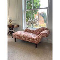 a couch sitting in front of a window next to a table with flowers on it