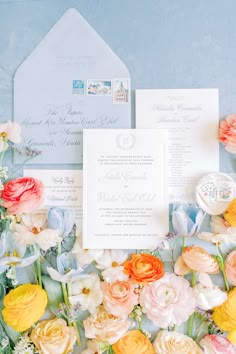 the wedding stationery is surrounded by colorful flowers