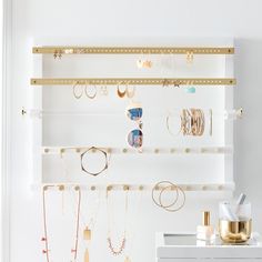 a white wall with gold jewelry hanging from it's sides and on the shelves