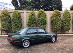 a green car parked in front of a fence