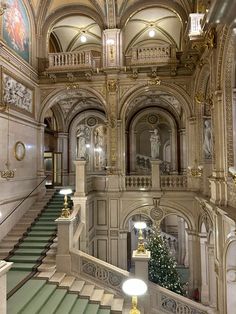 an ornately decorated building with stairs and paintings on the walls, along with a christmas tree