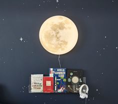 a bed with headphones and books on it in front of a wall mounted moon