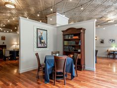 a dining room with wooden floors and white walls, has a painting on the wall