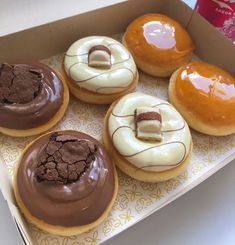 four donuts with chocolate frosting and white icing are in a cardboard box