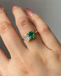 a woman's hand with an emerald and diamond ring