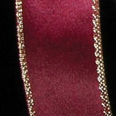 a close up of a red ribbon with beading on the end and a black background