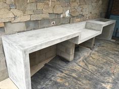 two concrete benches sitting next to each other in front of a stone wall and floor