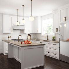 a kitchen with white cabinets and an island in the middle is seen from across the room