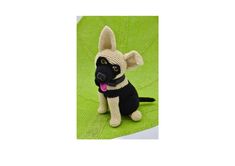 a knitted dog sitting on top of a green blanket with its tongue out and tongue out