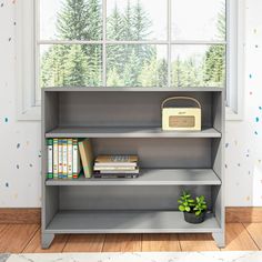 a book shelf with books and a radio on it in front of a large window