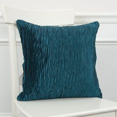 a white chair with a teal pillow on it