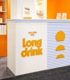 an orange and white counter with the words long drink on it in front of bookshelves