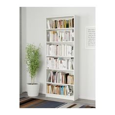 a white book shelf with books on it and a potted plant in the corner