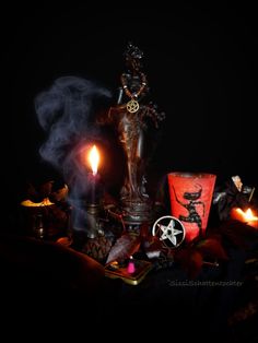 some candles and other items are on a black table with a statue in the background