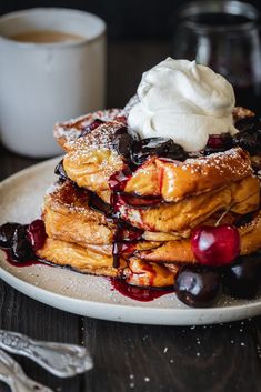 a stack of pancakes topped with whipped cream and cherries