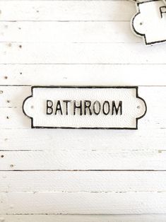 the bathroom sign is hanging on the white wood planks in front of the toilet