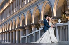 a bride and groom posing for a photo in front of an ornate building at night