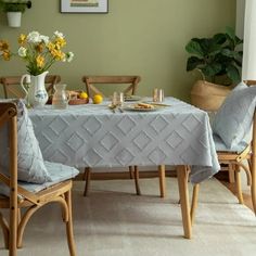 a dining room table with two chairs and a vase filled with yellow flowers on it